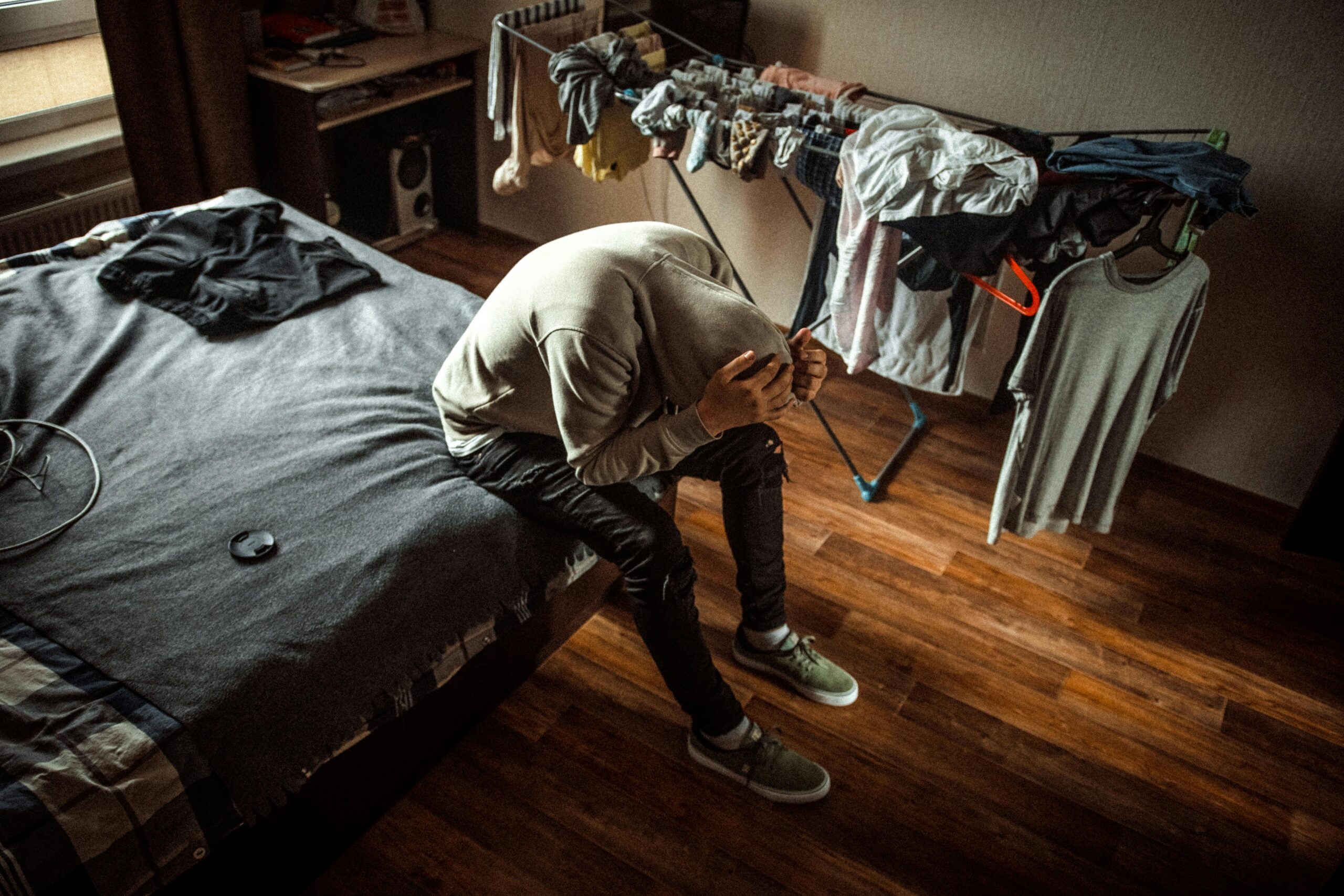 Ciągle mi smutno, nic mi się nie chce. Czy to już depresja? A person sits on a bed in distress, emphasizing mental health awareness.